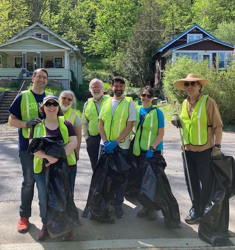 Clean up volunteers wearing reflective vests and posing with clean up supplies.